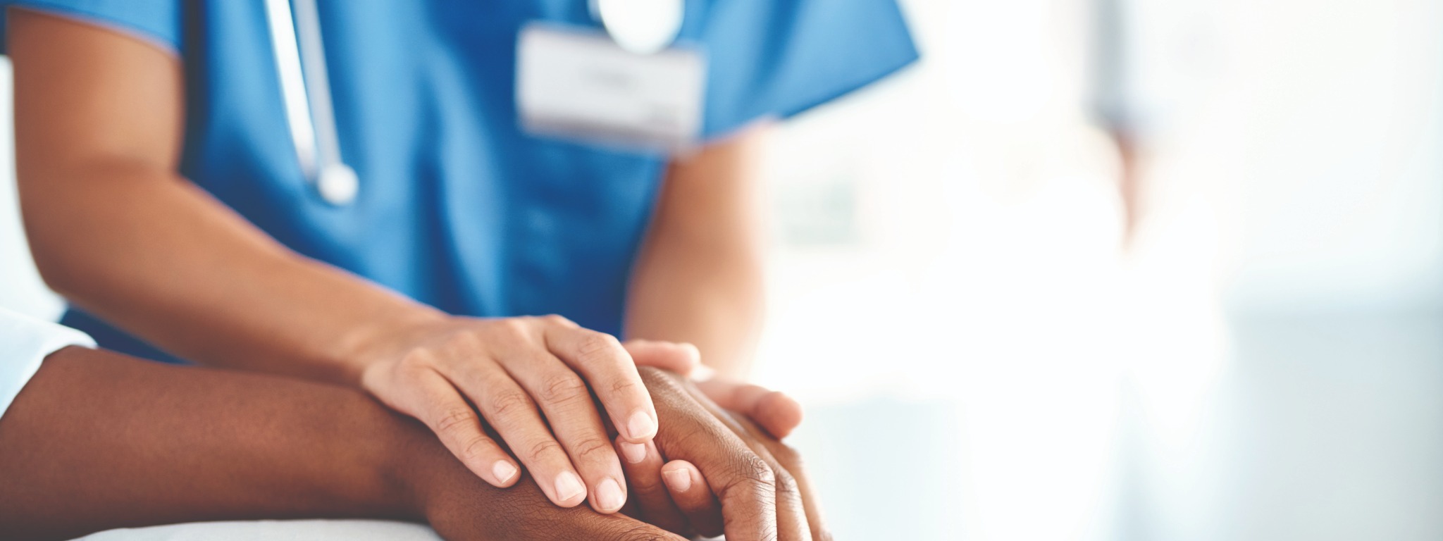 Medizinische Fachkraft hält unterstützend die Hände eines Patienten